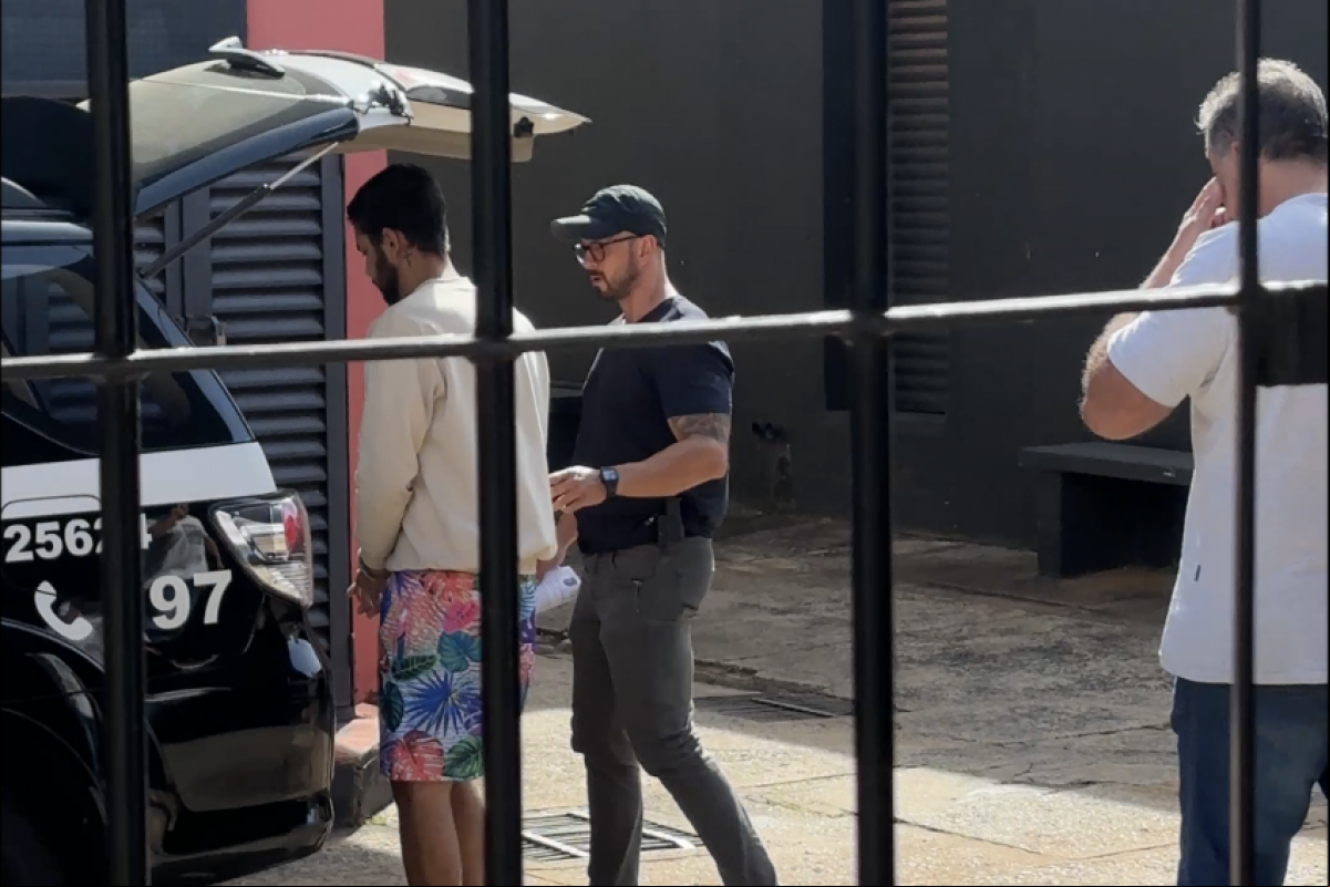 Momento em que acusado é colocado na viatura da Polícia Civil